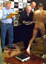 The heavily tattooed tough guy demurely stands on the scales covering his cock and balls by Ruggerbugger