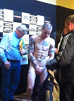 The heavily tattooed tough guy demurely stands on the scales covering his cock and balls by Ruggerbugger
